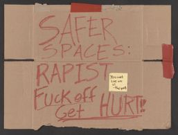 Carboard sign that reads "Safer Spaces: Rapists Fuck Off"
